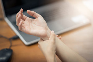 Woman holding her wrist pain from using computer. Office syndrome